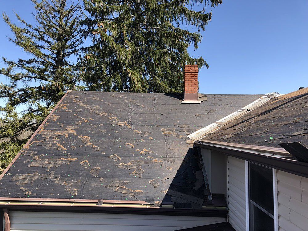 A roof with a chimney on top of it and a tree in the background.