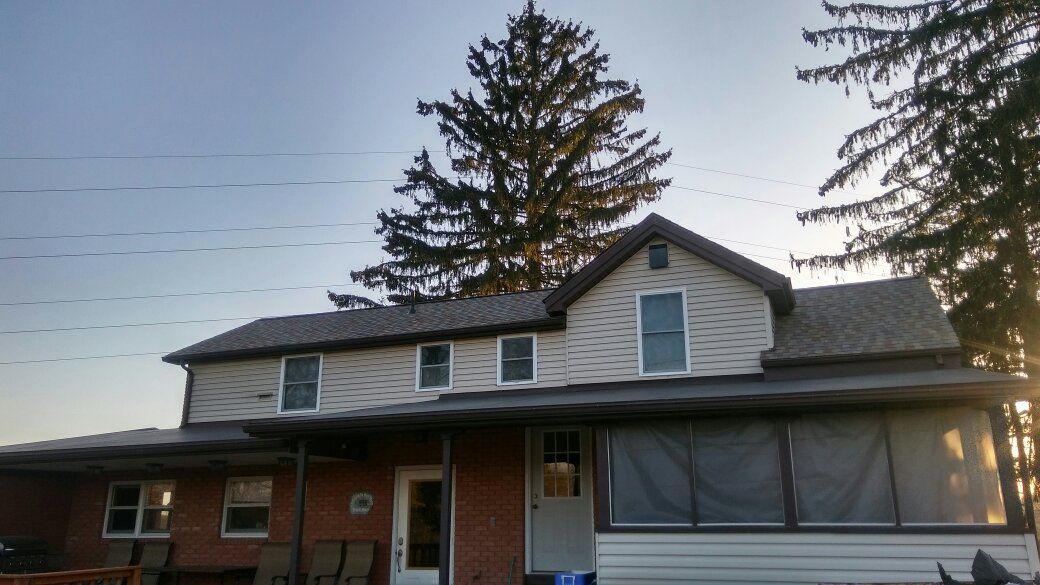A house with a screened in porch and a tree in the background
