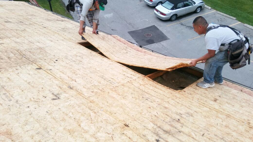 Two men are working on the roof of a house.