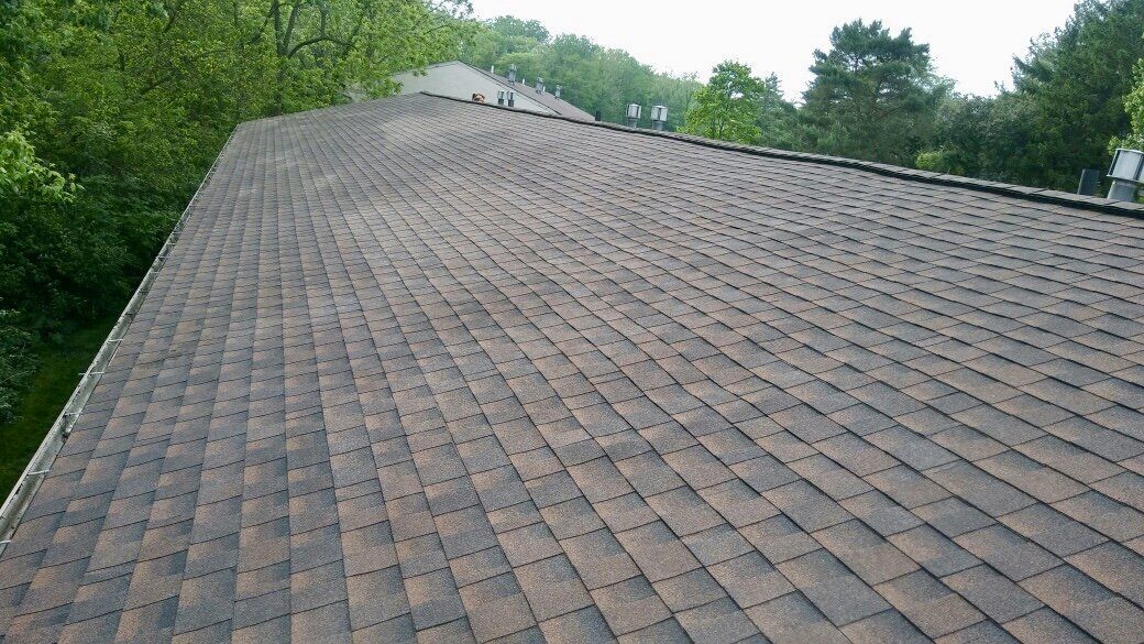 A large roof with a lot of shingles on it is surrounded by trees.