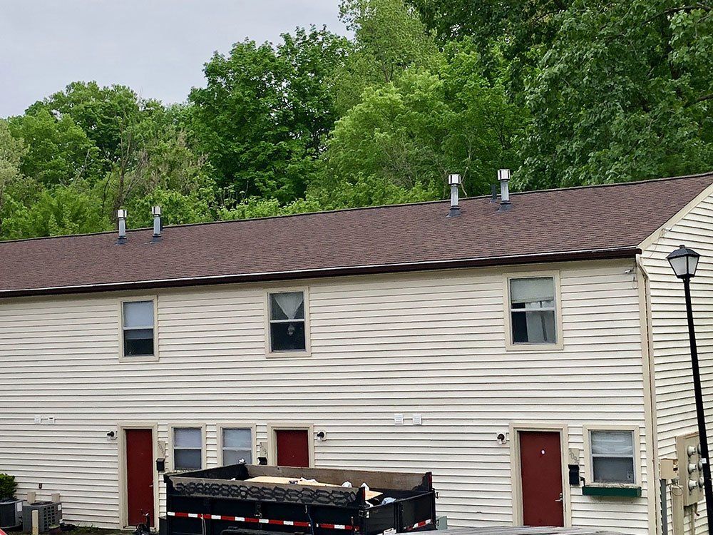 A dumpster is parked in front of a white house