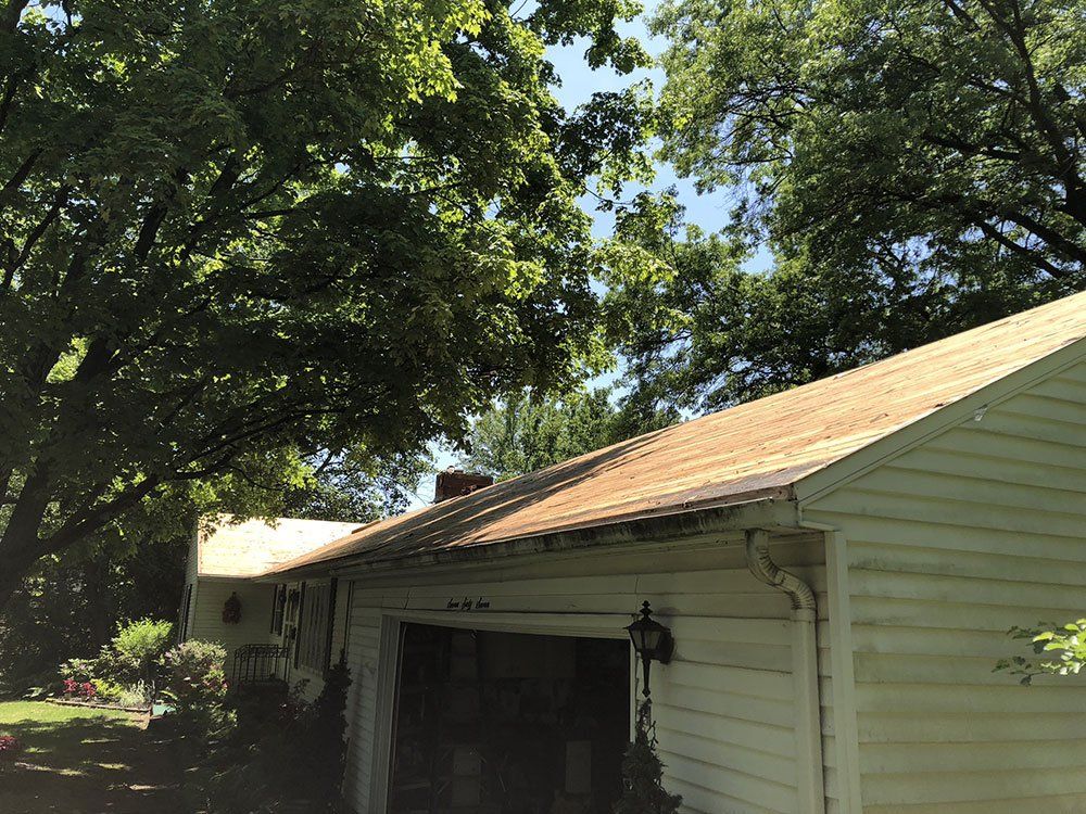 A white house with a brown roof and a garage.