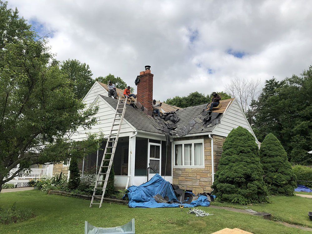 A group of people are working on the roof of a house.