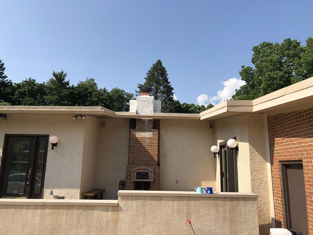 A white house with a brick chimney on the side of it.