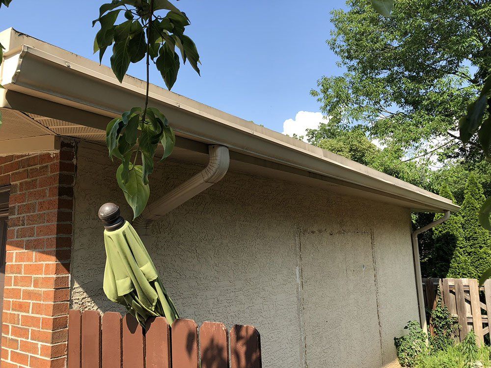 A green umbrella is hanging from the side of a house.