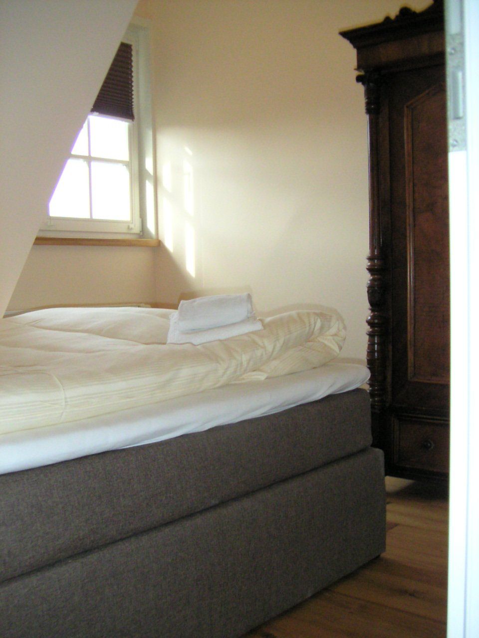 Een slaapkamer met een bed, een raam en een kledingkast