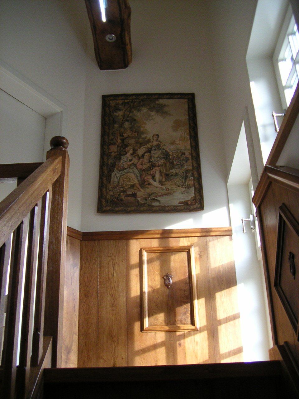 Een houten trap met daarboven een schilderij aan de muur