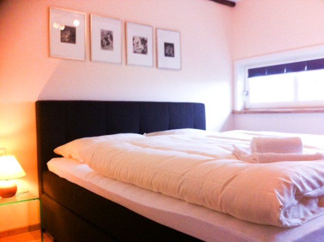 Een bed met witte lakens en een zwart hoofdeinde in een slaapkamer