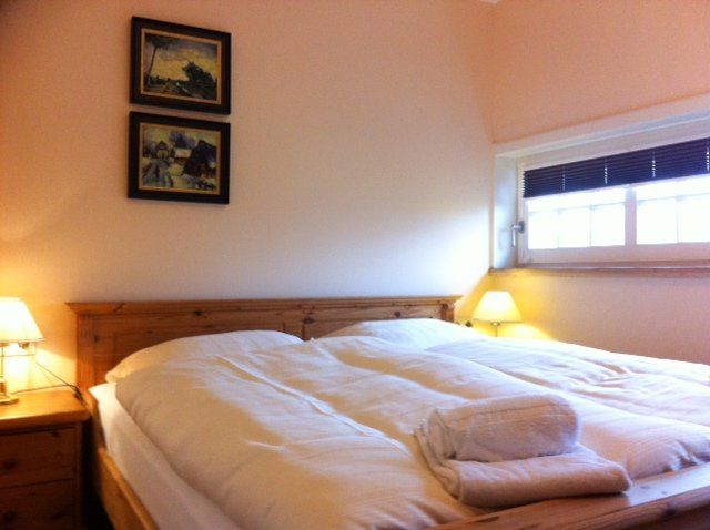 Een slaapkamer met twee schilderijen aan de muur boven het bed