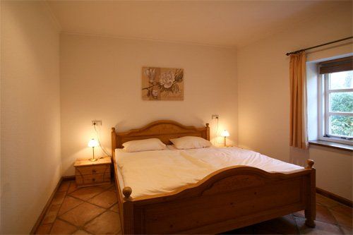 Een slaapkamer met een houten bed en een raam