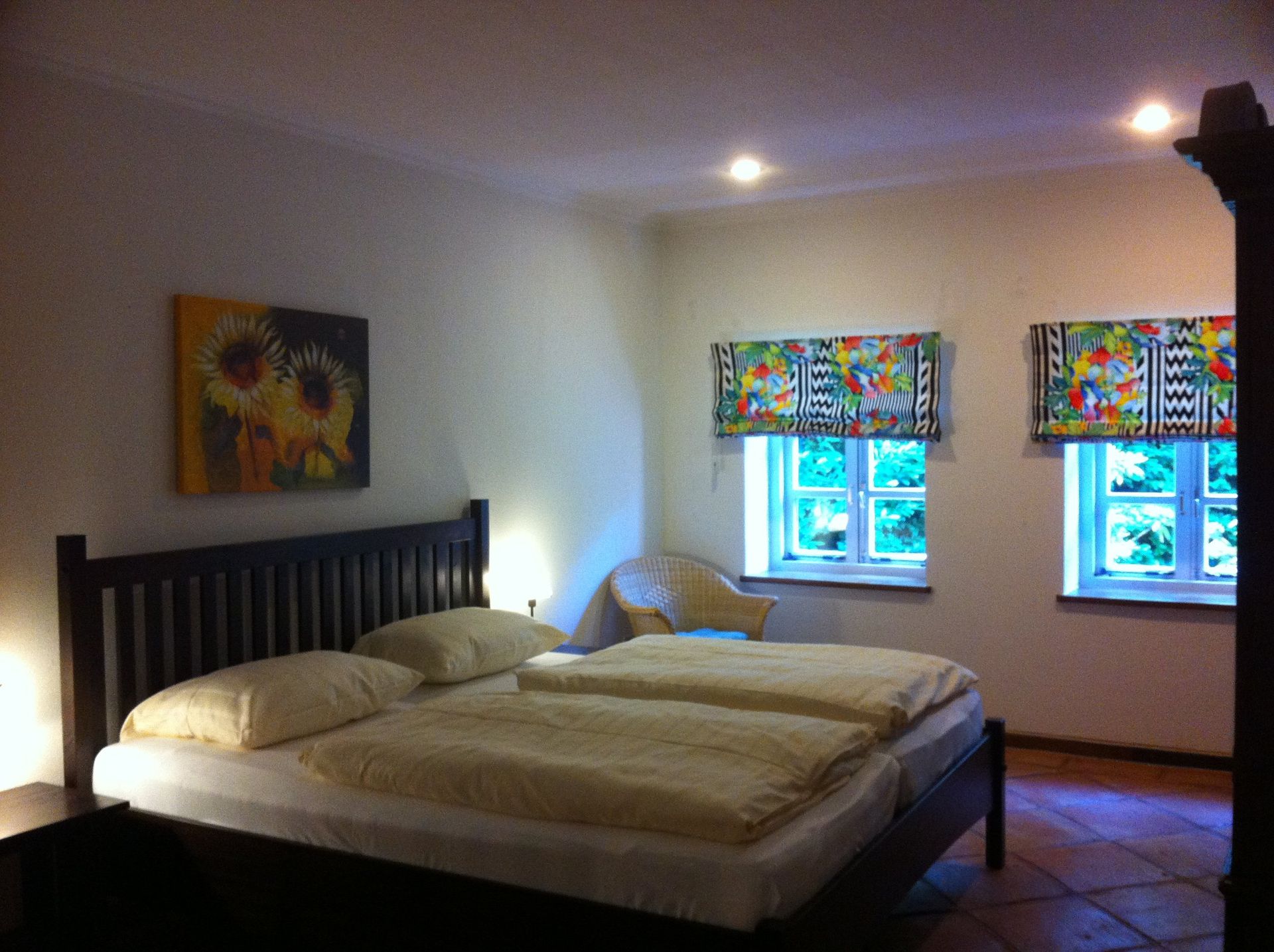 Een slaapkamer met een groot bed en twee ramen