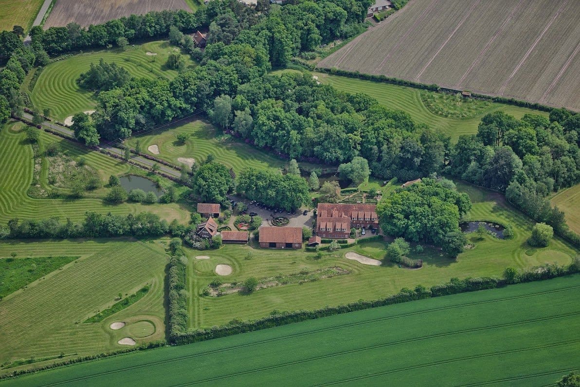 Eine Luftaufnahme eines großen Hauses, umgeben von Feldern und Bäumen.