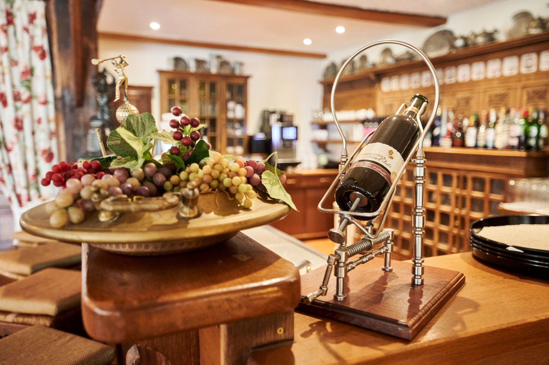 Auf einem Holztisch steht eine Flasche Wein neben einer Schale mit Weintrauben.