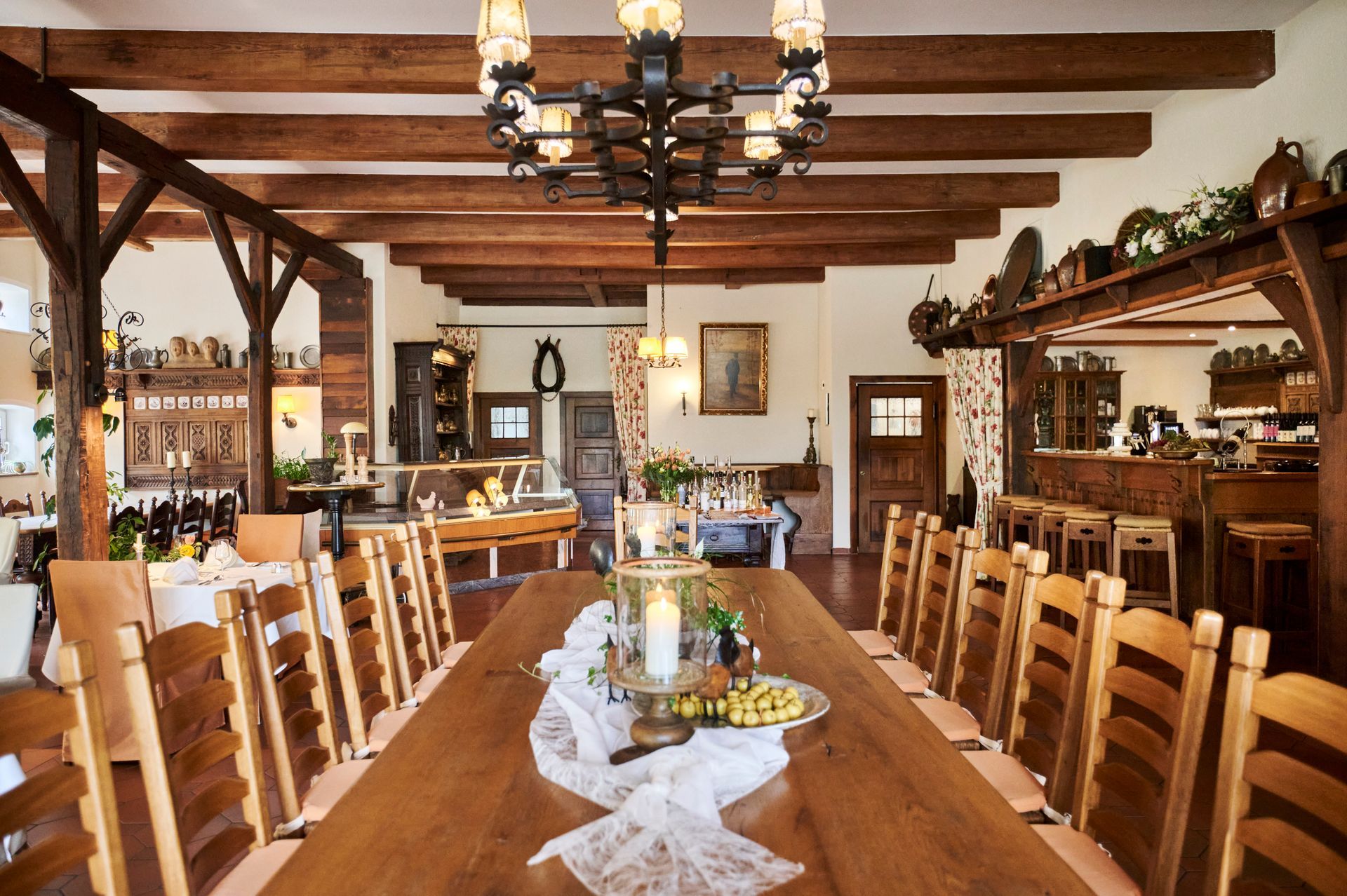 Ein langer Holztisch in einem Restaurant, von dessen Decke ein Kronleuchter hängt.