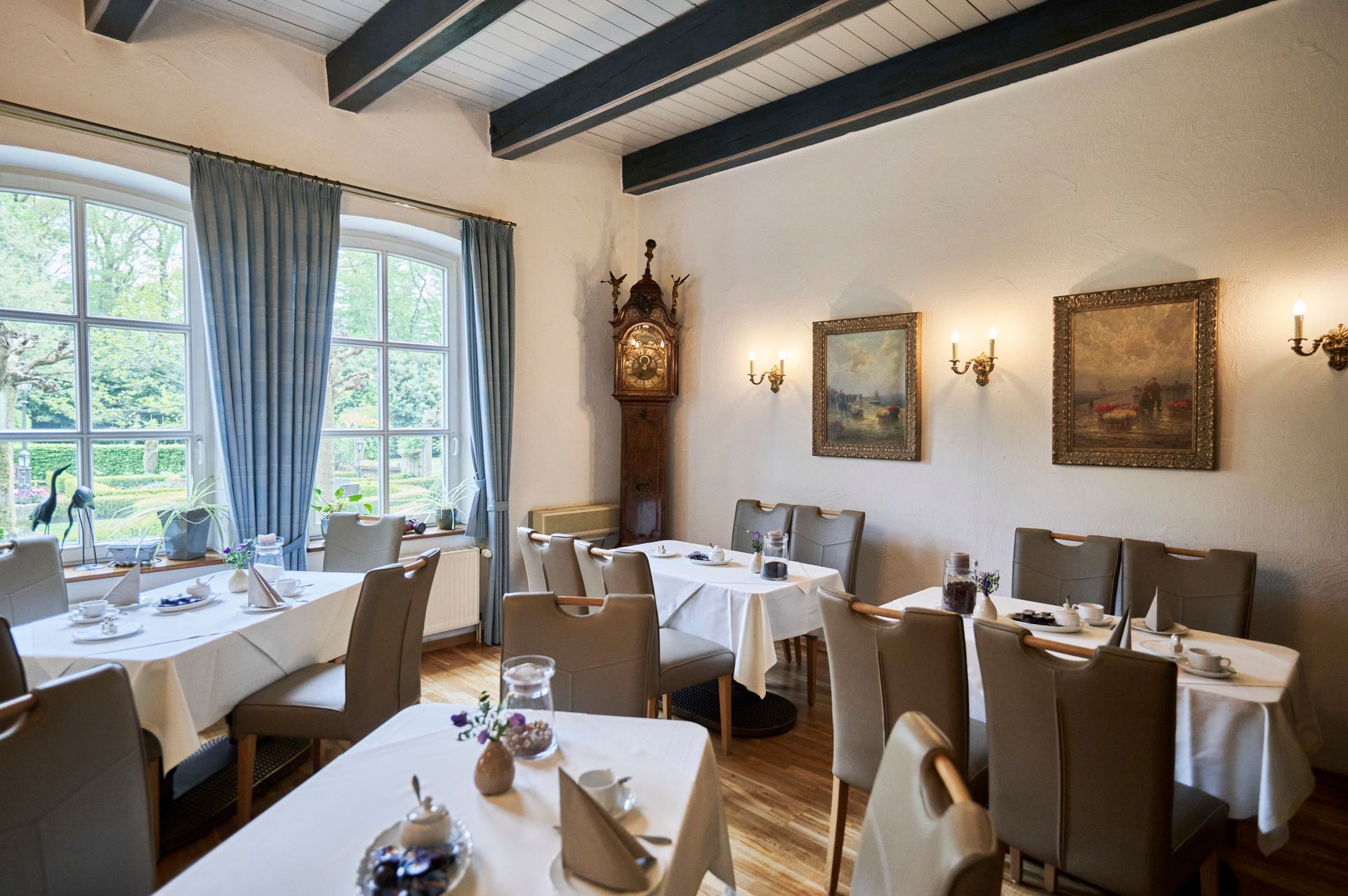 Ein Esszimmer mit Tischen und Stühlen und einer Uhr an der Wand.