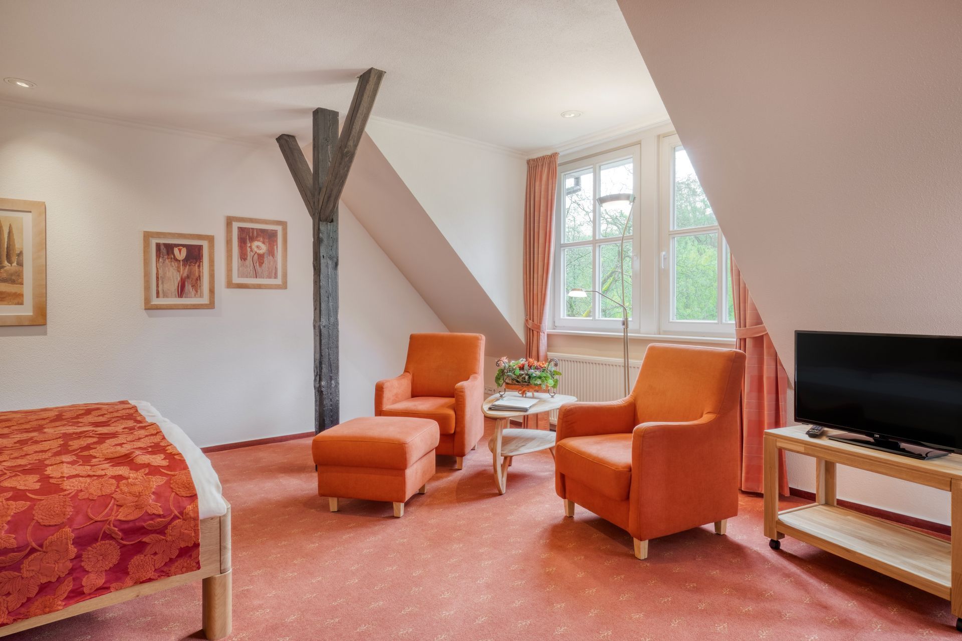 Ein Hotelzimmer mit einem Bett, Stühlen und einem Flachbildfernseher.