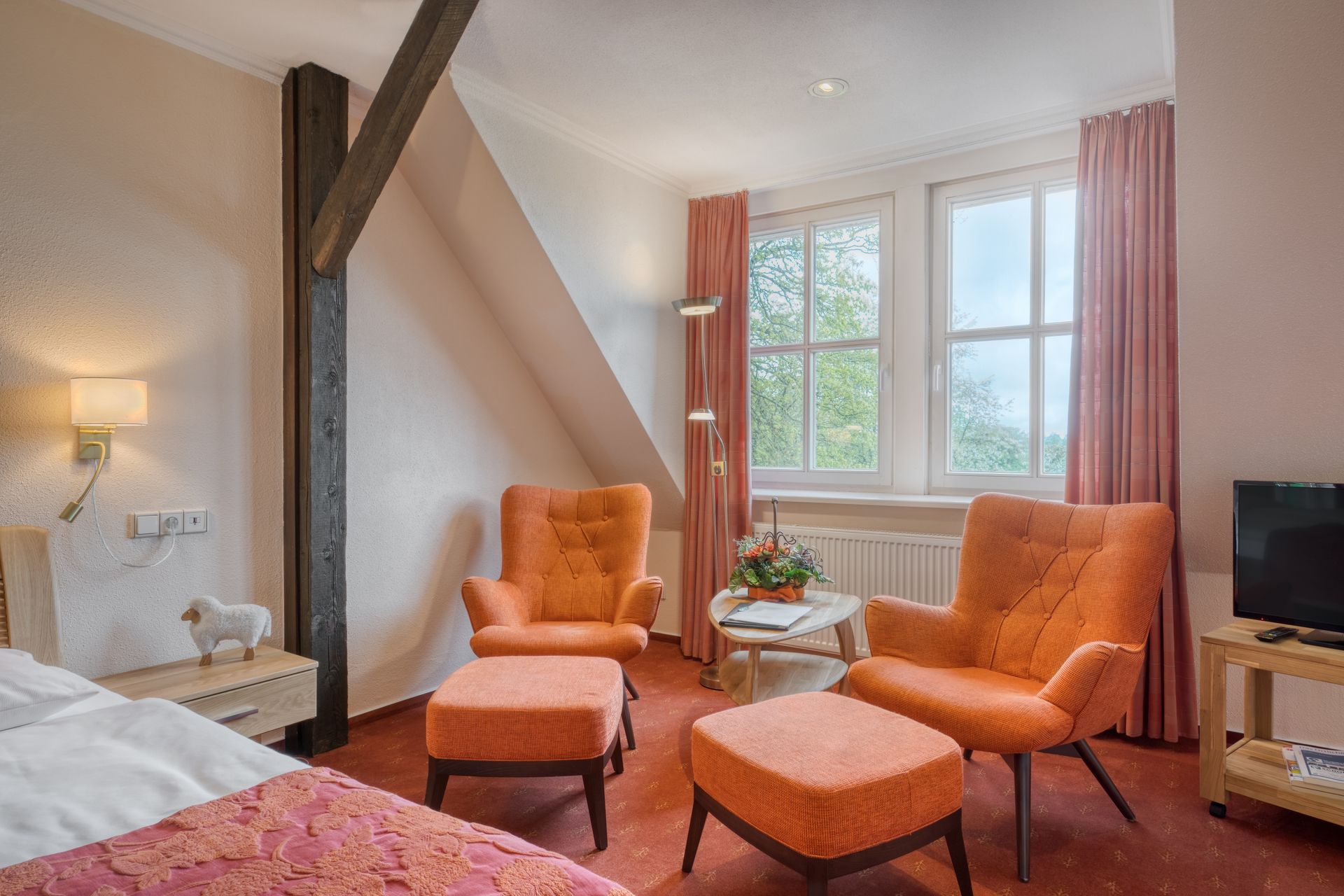 Ein Hotelzimmer mit einem Bett, Stühlen, Ottomanen und einem Fernseher.