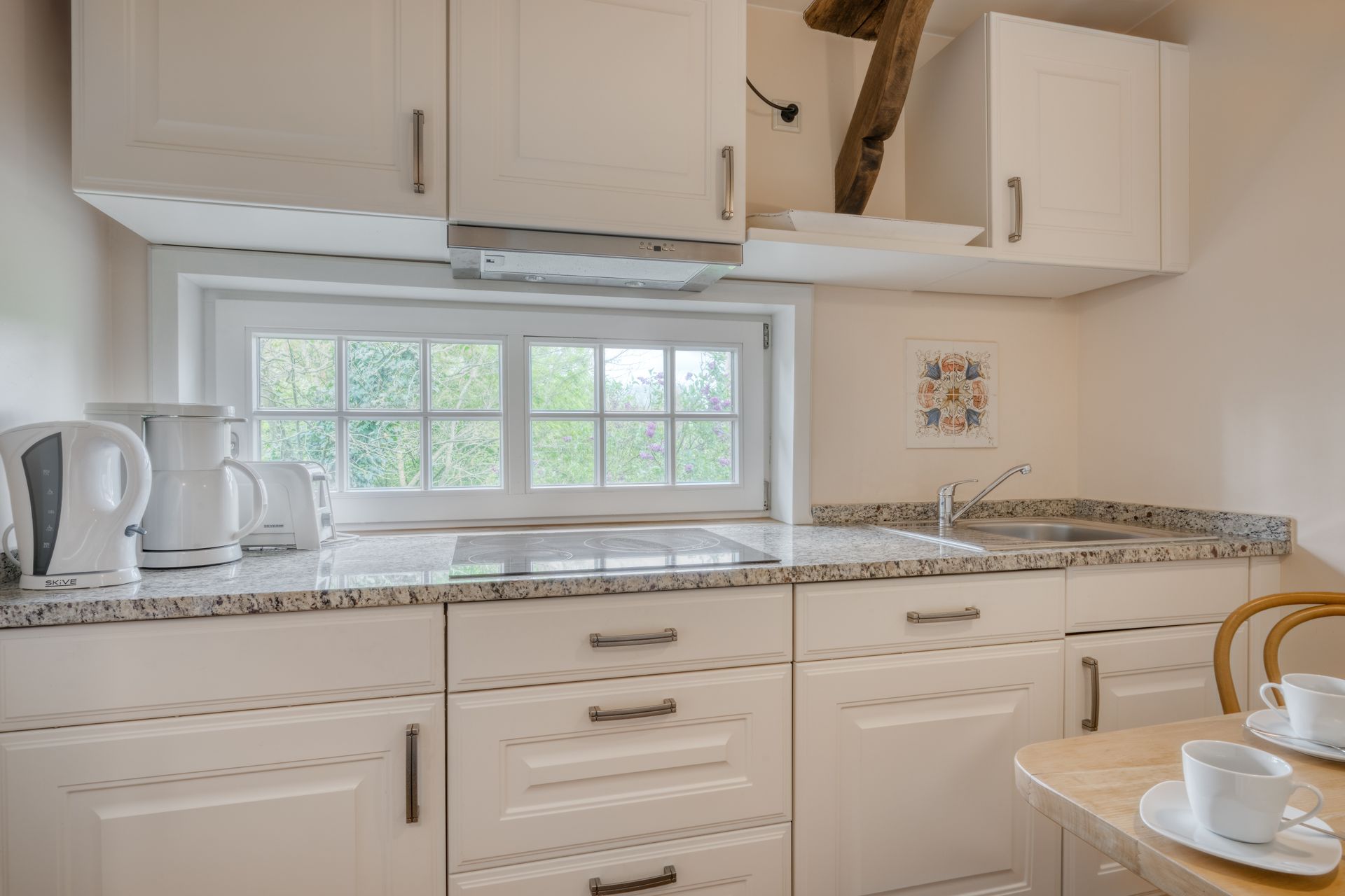 Een keuken met witte kasten en een tafel met een kopje koffie erop.