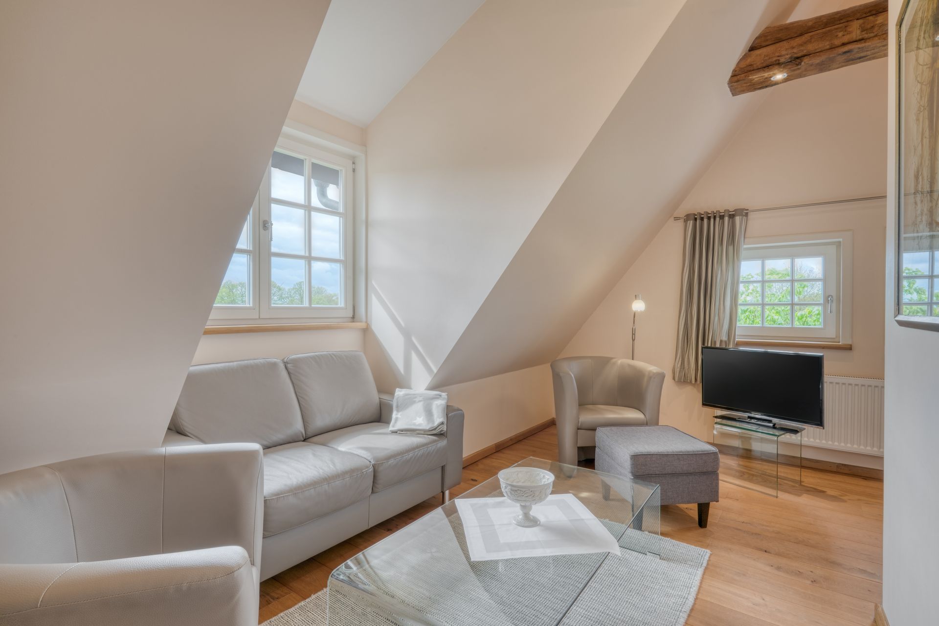 Ein Wohnzimmer mit Sofa, Stühlen, Couchtisch und Fernseher.