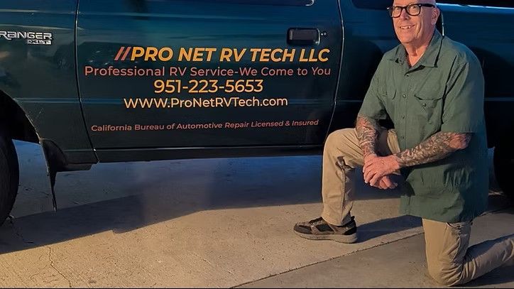 A technician kneels beside a dark green service truck with 