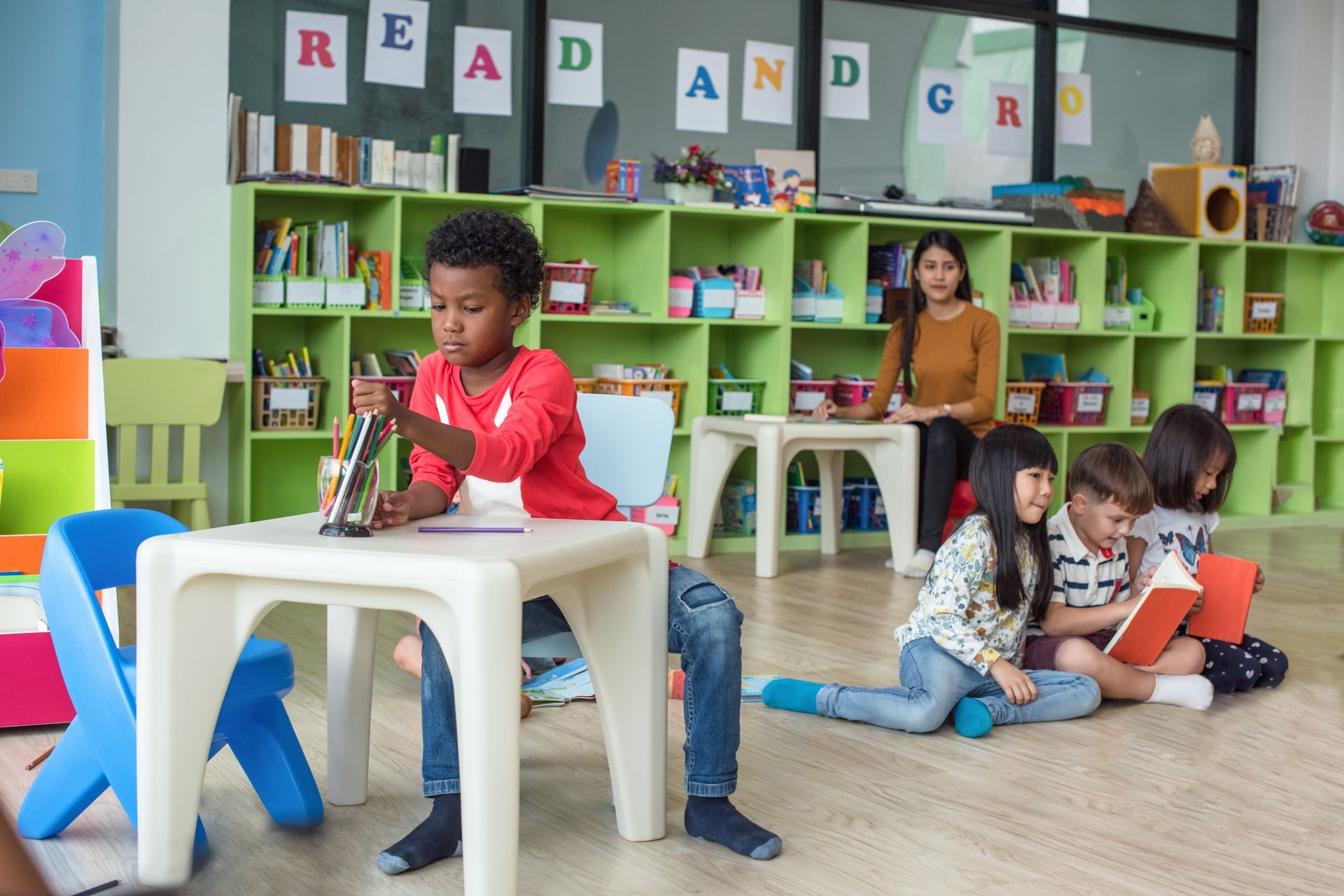 Young children focused on a drawing and reading activities during preschool class.