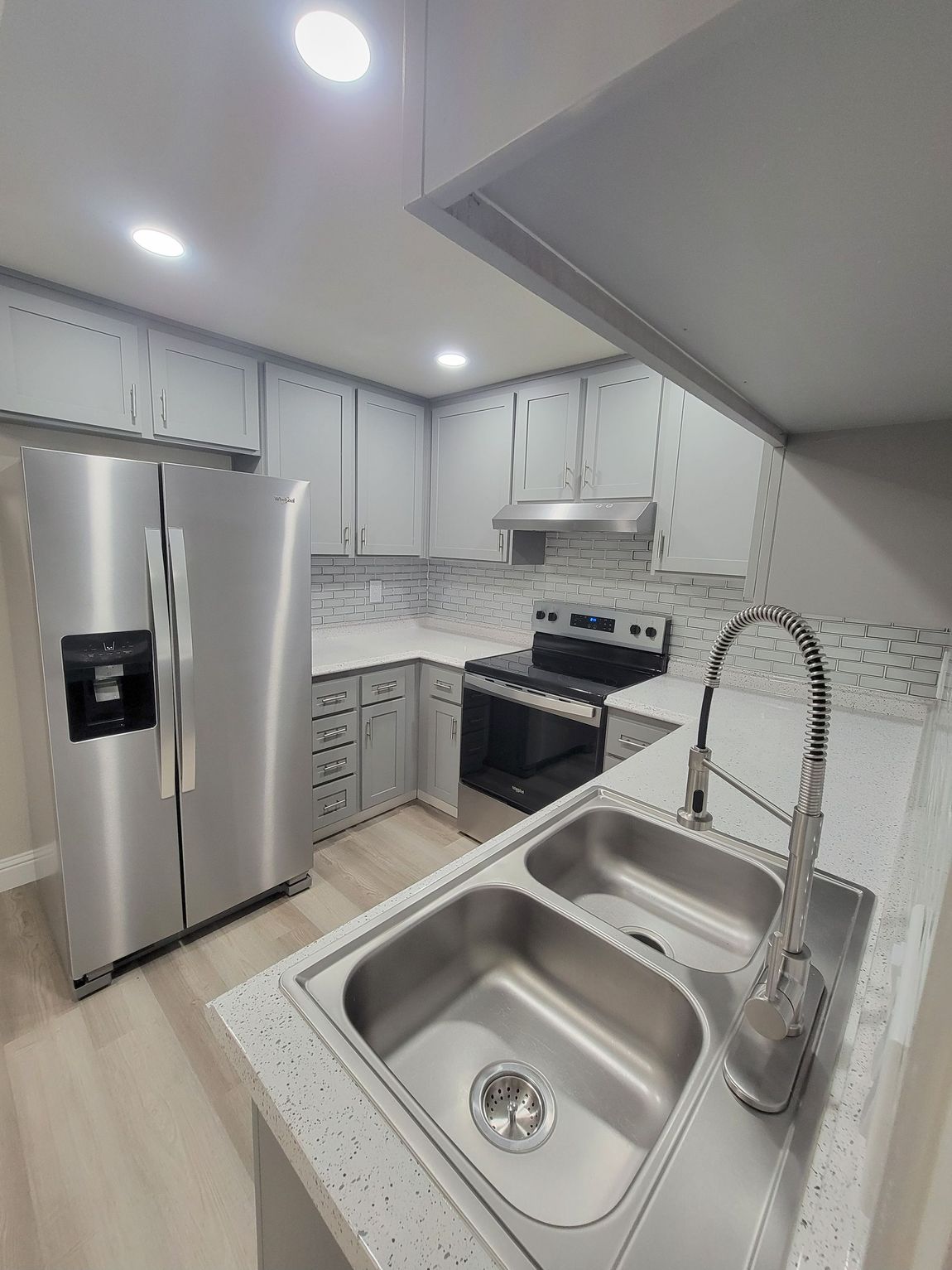 Kitchen with gray cabinets, stainless steel appliances, and a double sink.