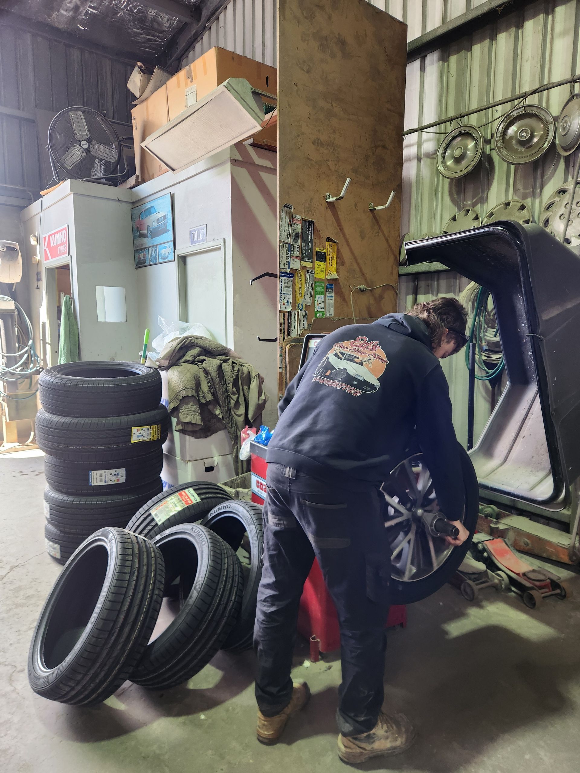 A man is standing next to a pile of tires in a garage.