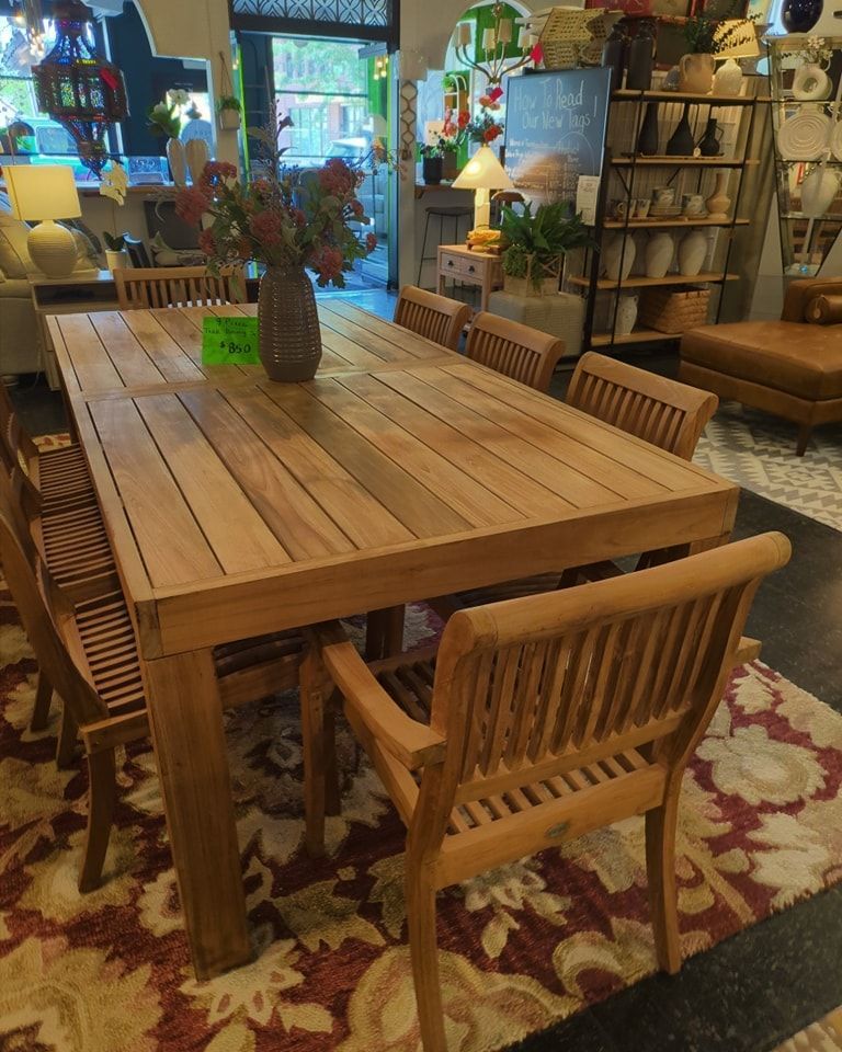 Wooden dining table with six chairs, flowers, inside a store.