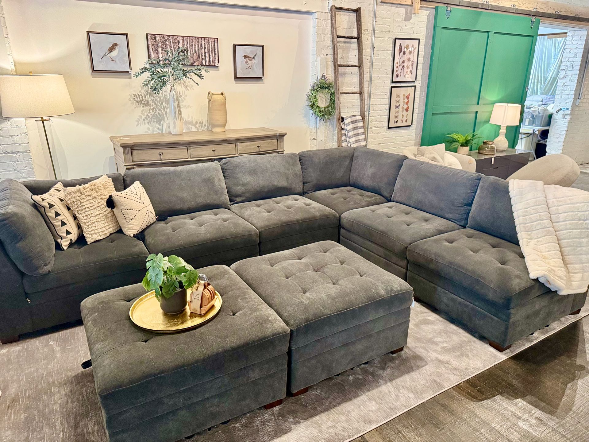 Gray sectional sofa with ottomans in a living room, with decorative pillows and wall art.