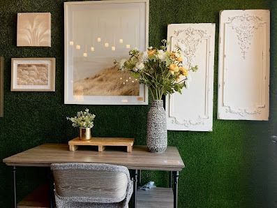 Desk with wall decor and flowers against a green moss wall.