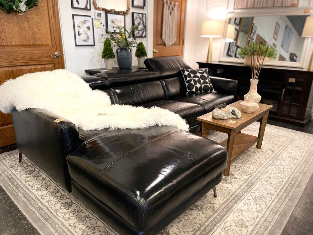 Black leather sectional sofa with a fluffy white throw rug.