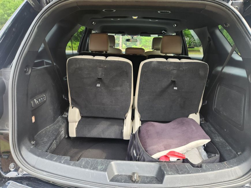 Car trunk with two upright rear seats and a folded blanket on the cargo floor.
