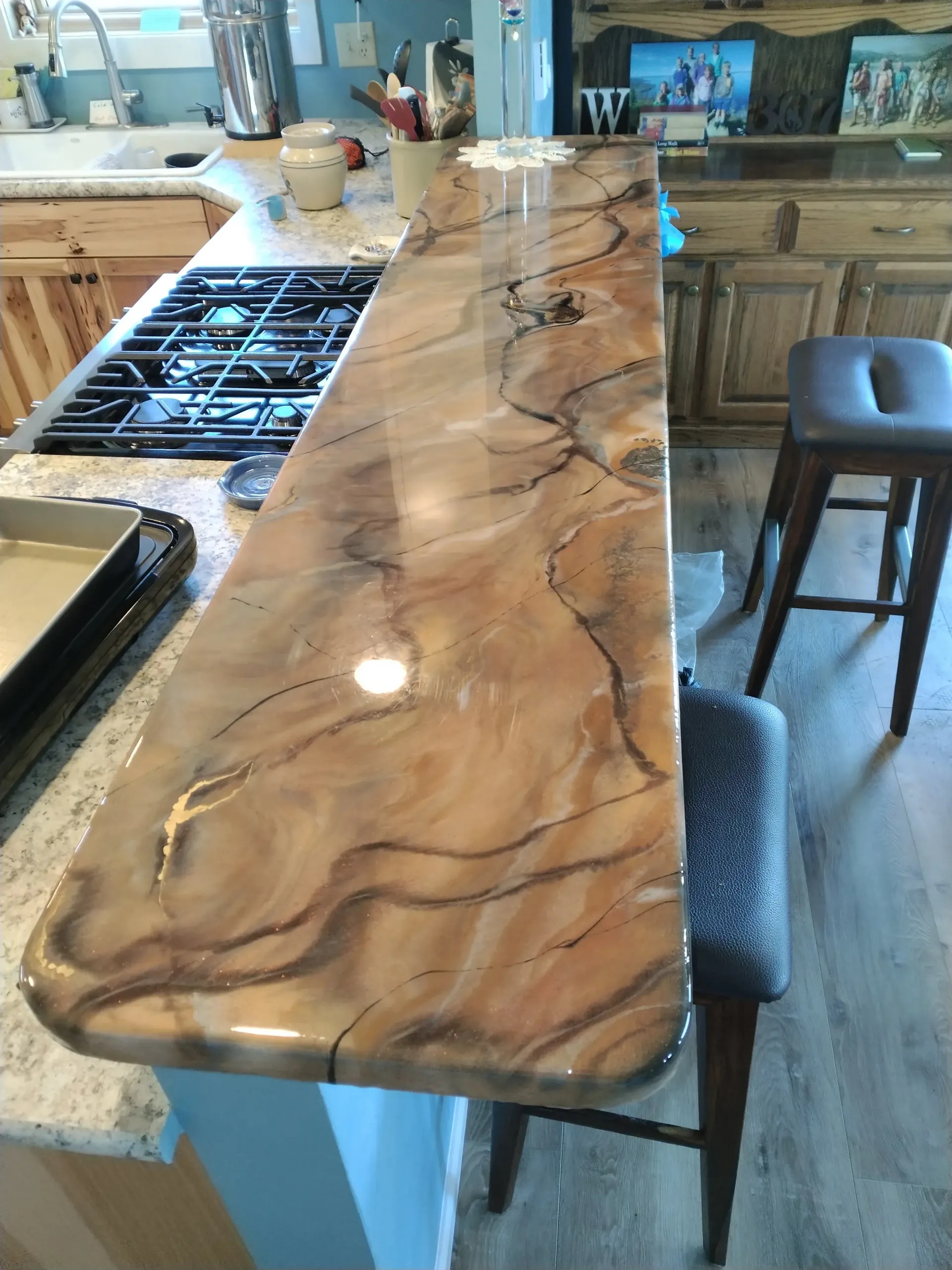 A kitchen counter with a stove top oven and stools.