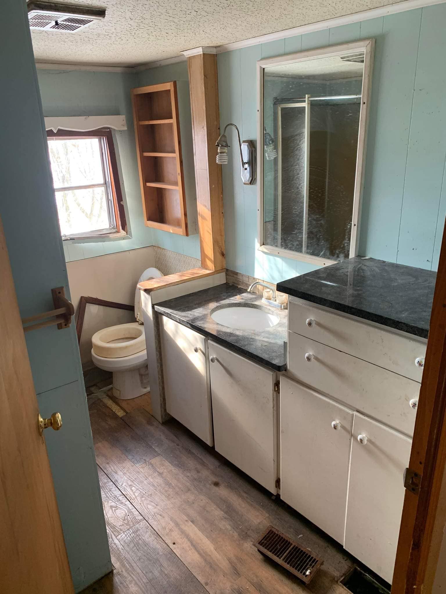 Small bathroom with sink, toilet, vanity, mirror, blue walls, and wooden floor.