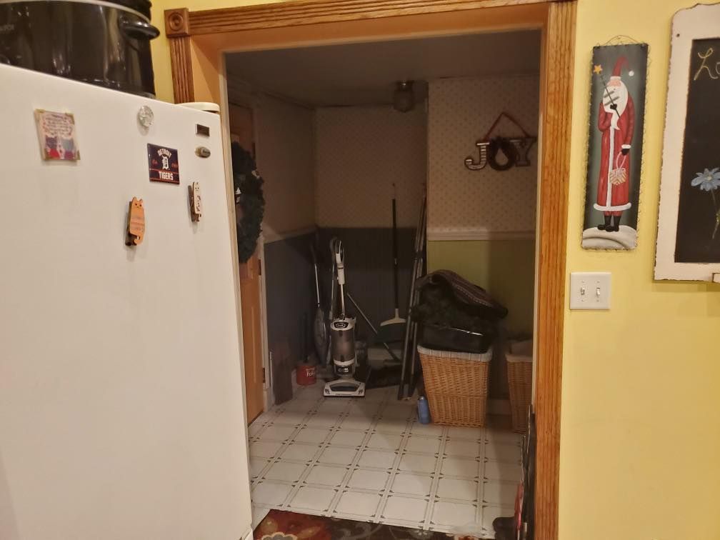 Kitchen doorway with a vacuum cleaner in the hallway and a white refrigerator on the left