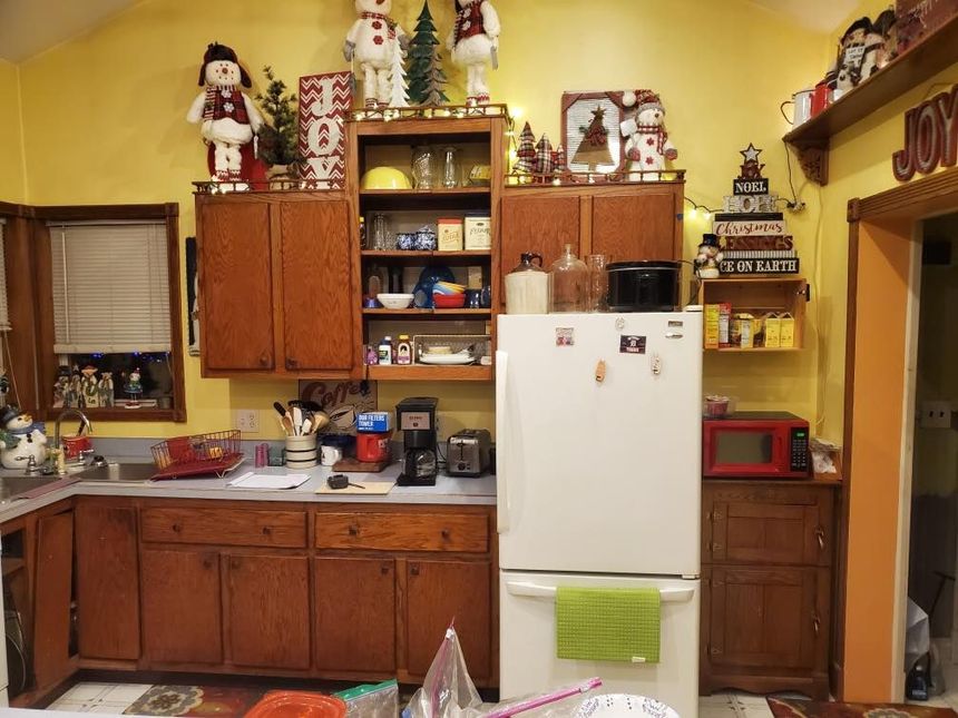 Cozy kitchen with wooden cabinets, white refrigerator, yellow walls, and holiday decorations above the counters.