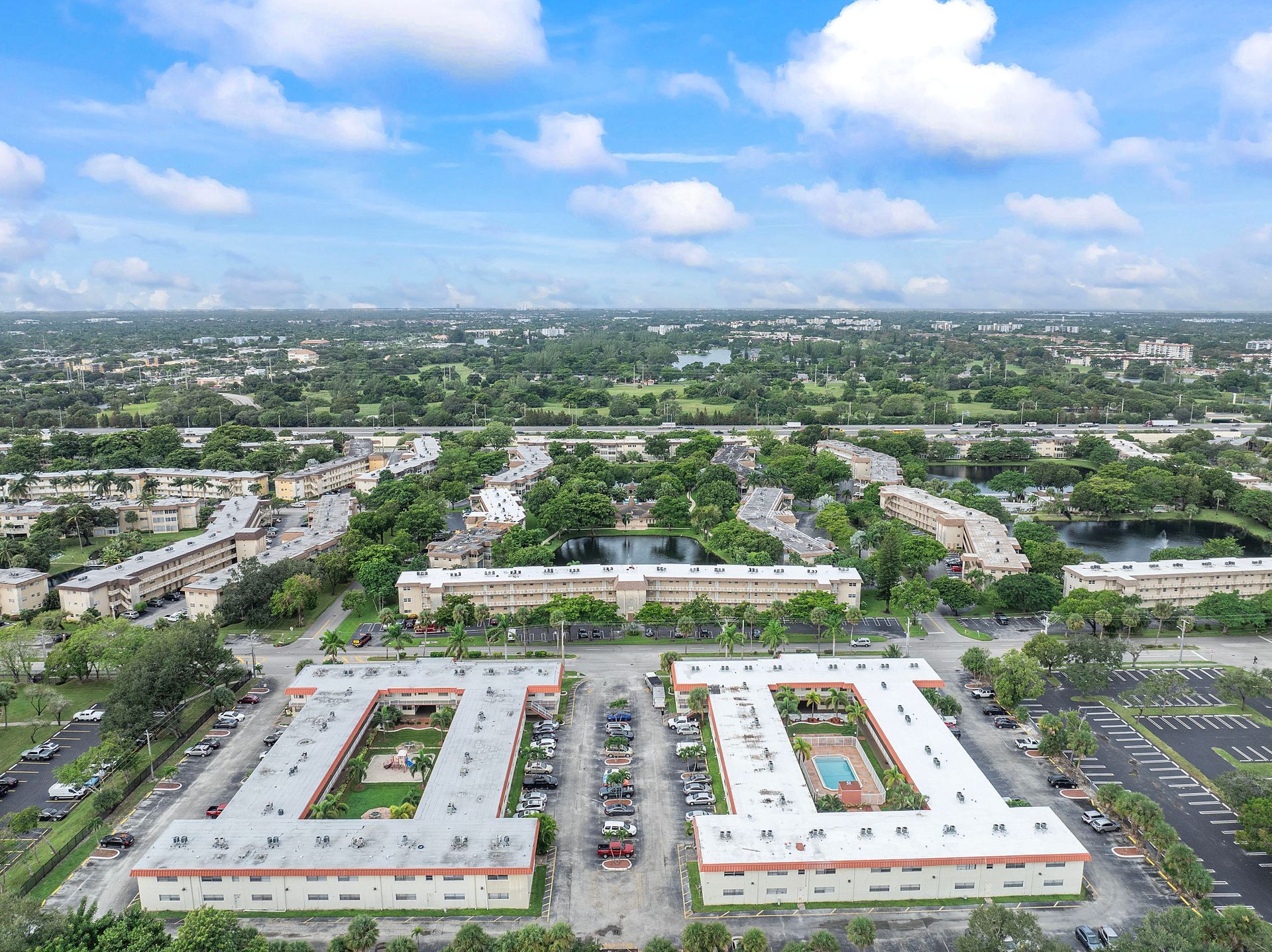 An aerial view of a large apartment complex in a city surrounded by trees.