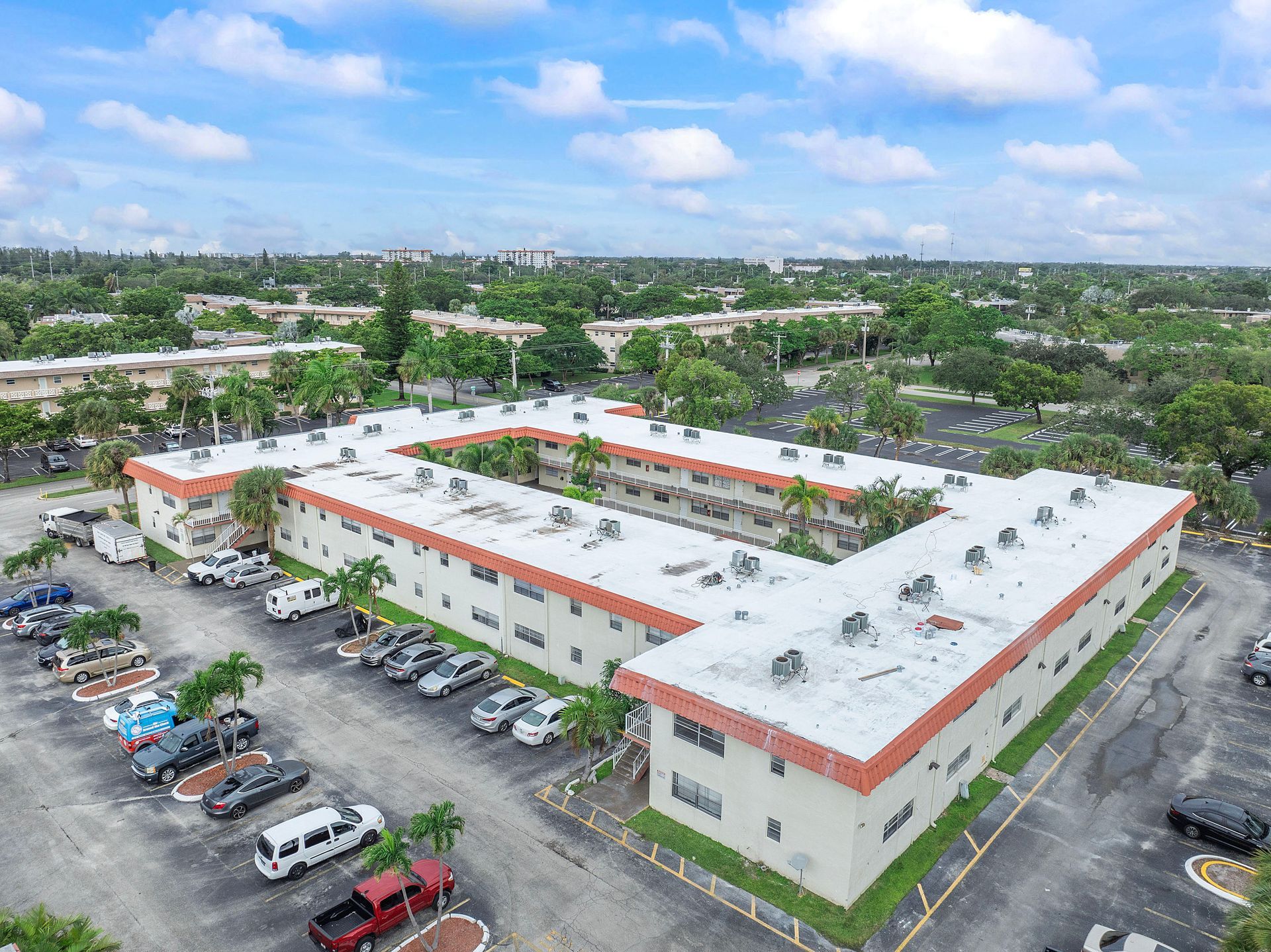An aerial view of a large apartment building with a parking lot in front of it.