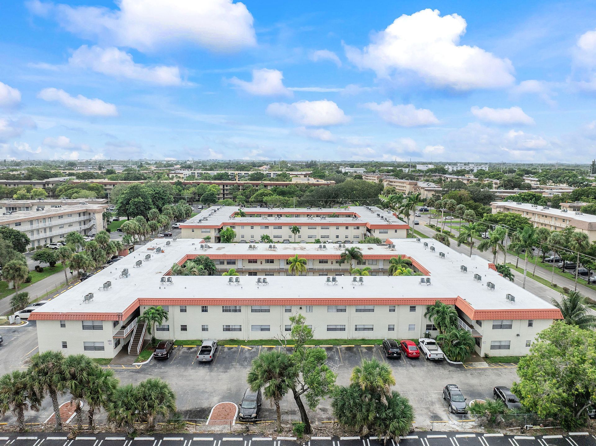 An aerial view of a large apartment building with a lot of cars parked in front of it.