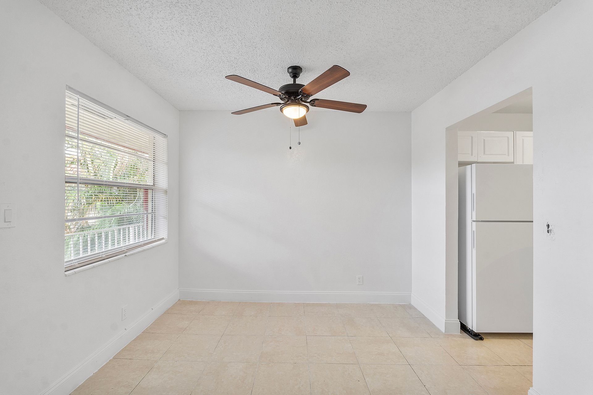 An empty room with a ceiling fan and a window.