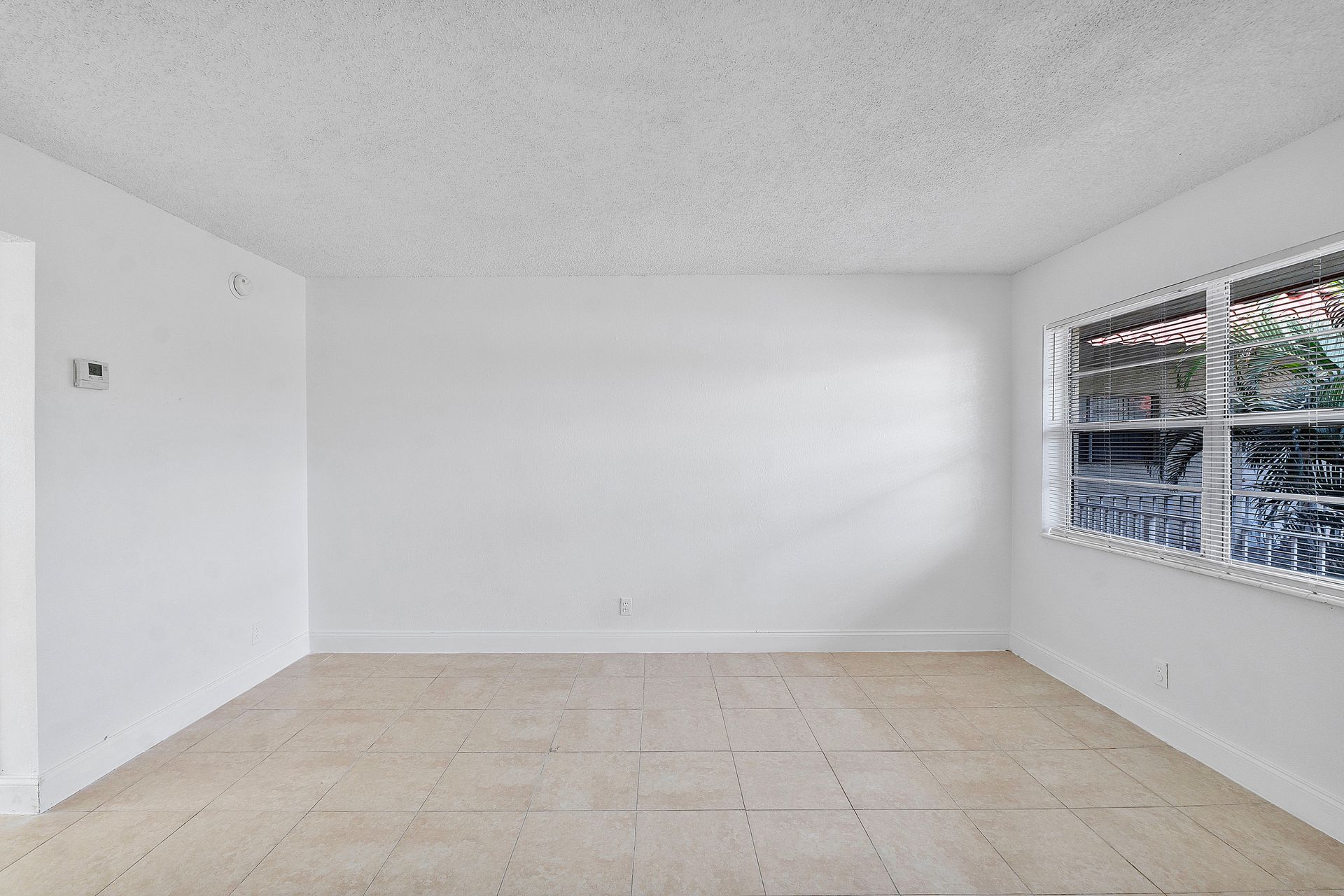 An empty living room with white walls and two windows.