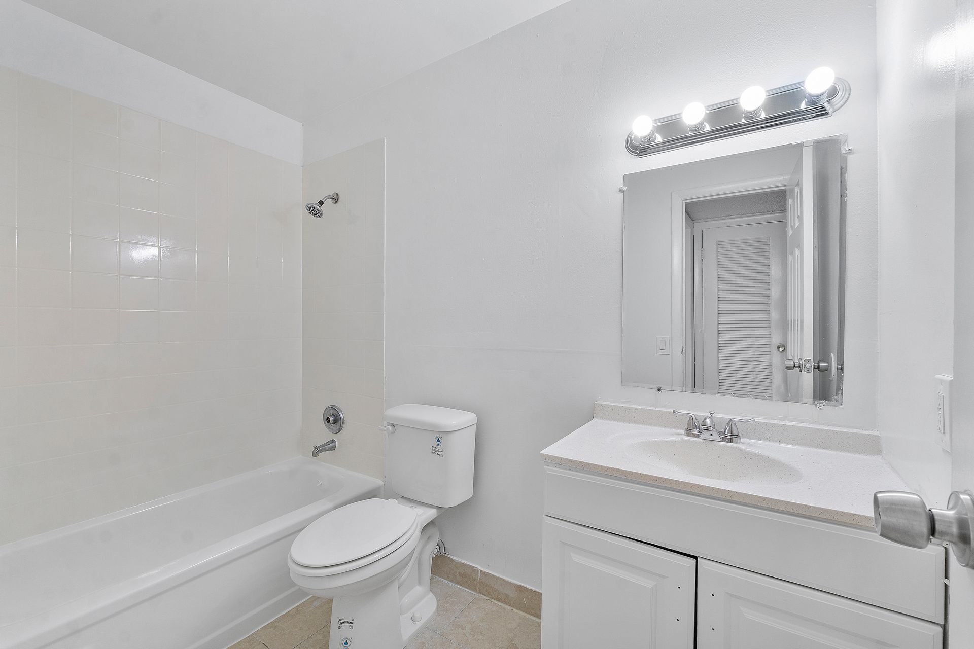A bathroom with a toilet , sink , bathtub and mirror.
