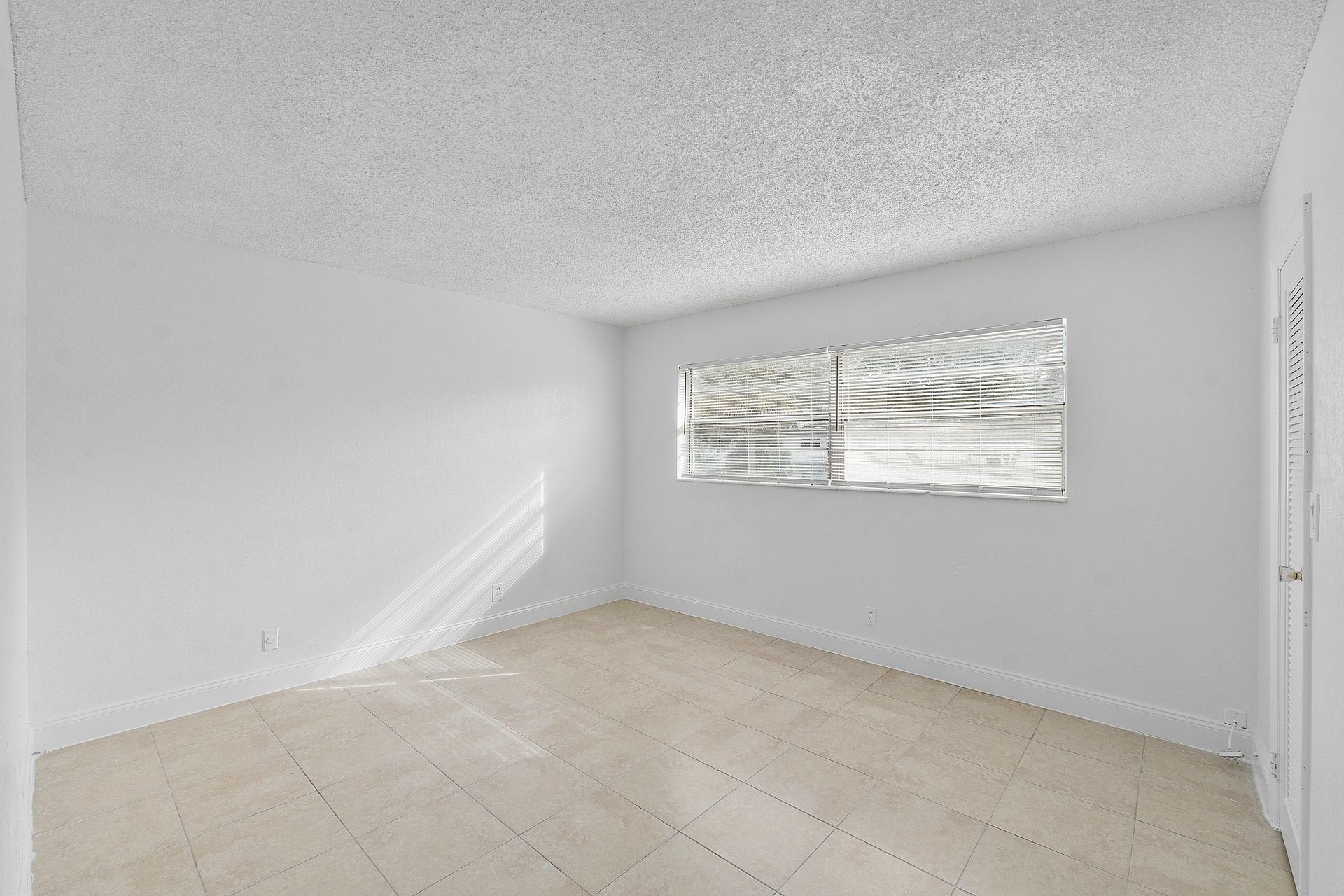 An empty room with white walls and a window.