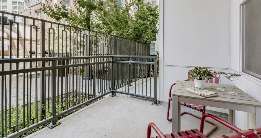 A balcony with a table and chairs and a fence.