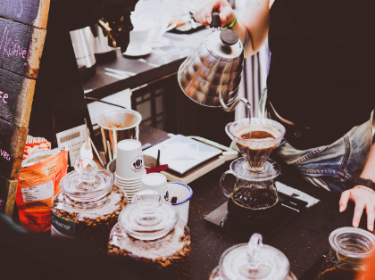 A person is pouring coffee into a glass cup.