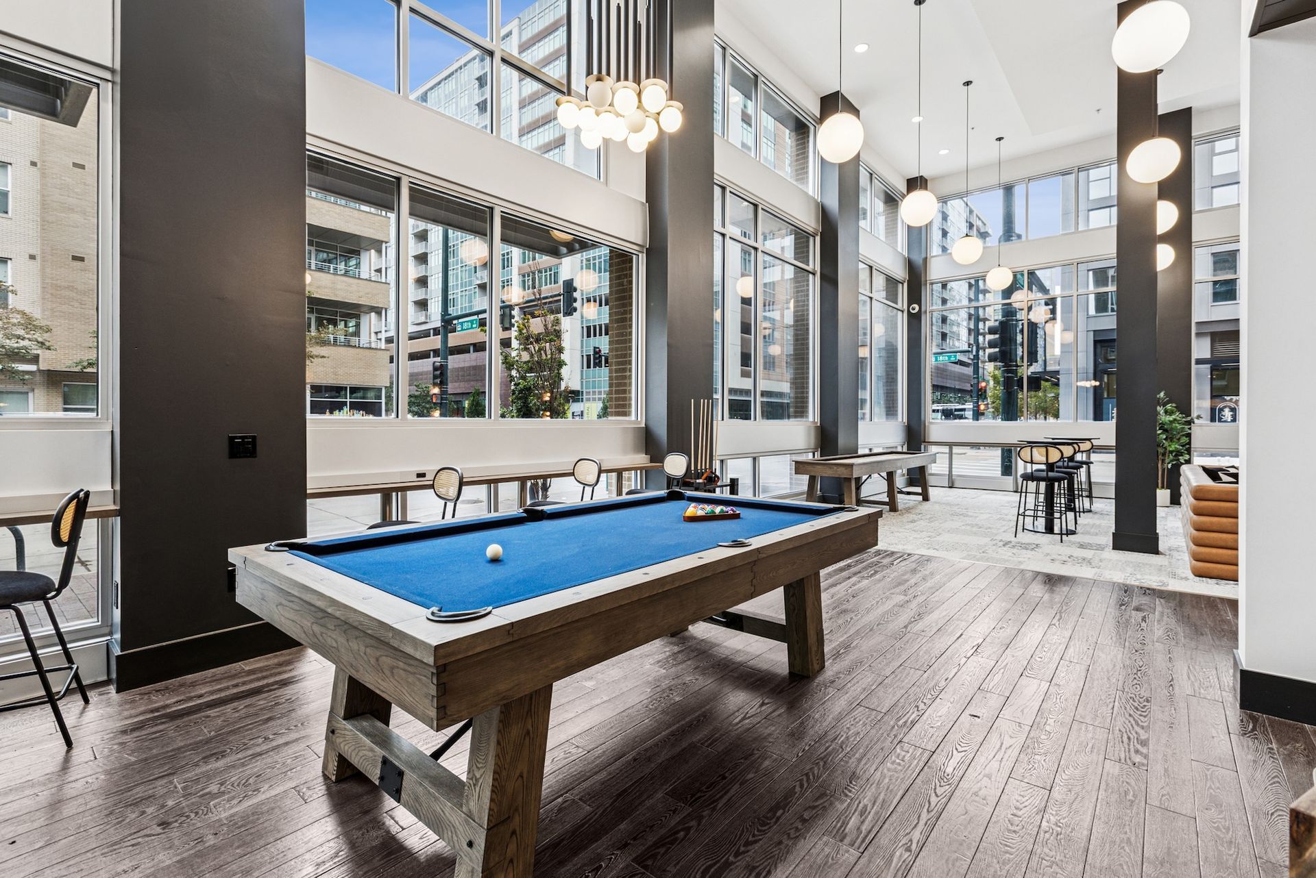 A bright game room with a pool table, windows, and modern light fixtures.