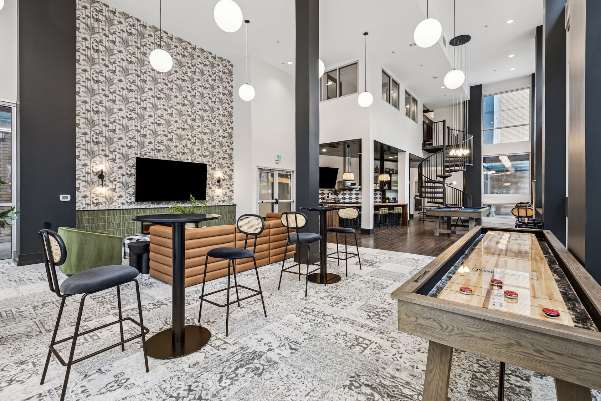 Modern lounge area with shuffleboard, high-top tables, and a patterned rug.