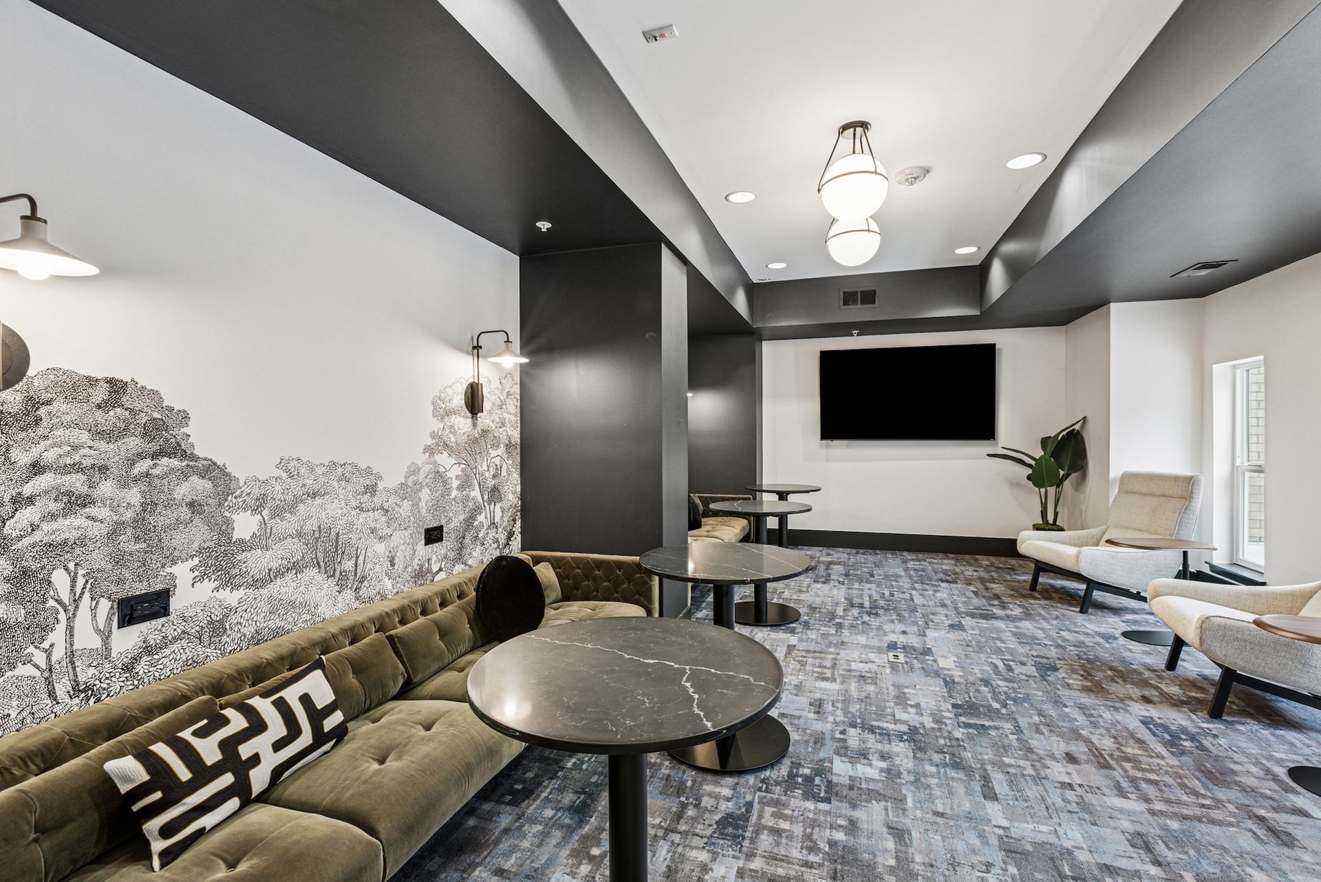 Lounge with gray and white decor: a sofa, armchairs, tables, a large TV, and a mural.