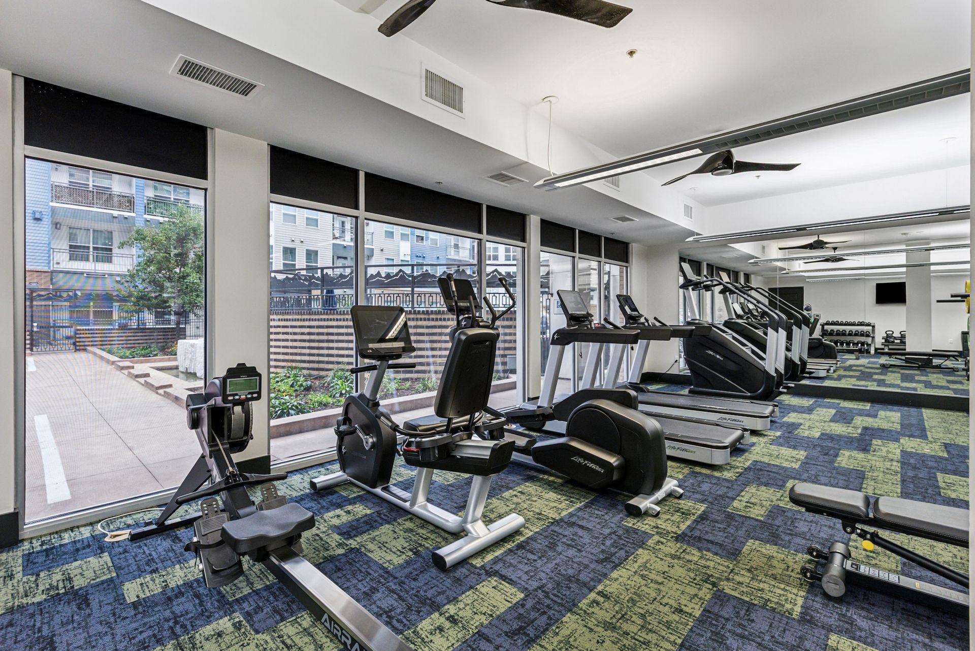 Gym with exercise equipment and large windows.
