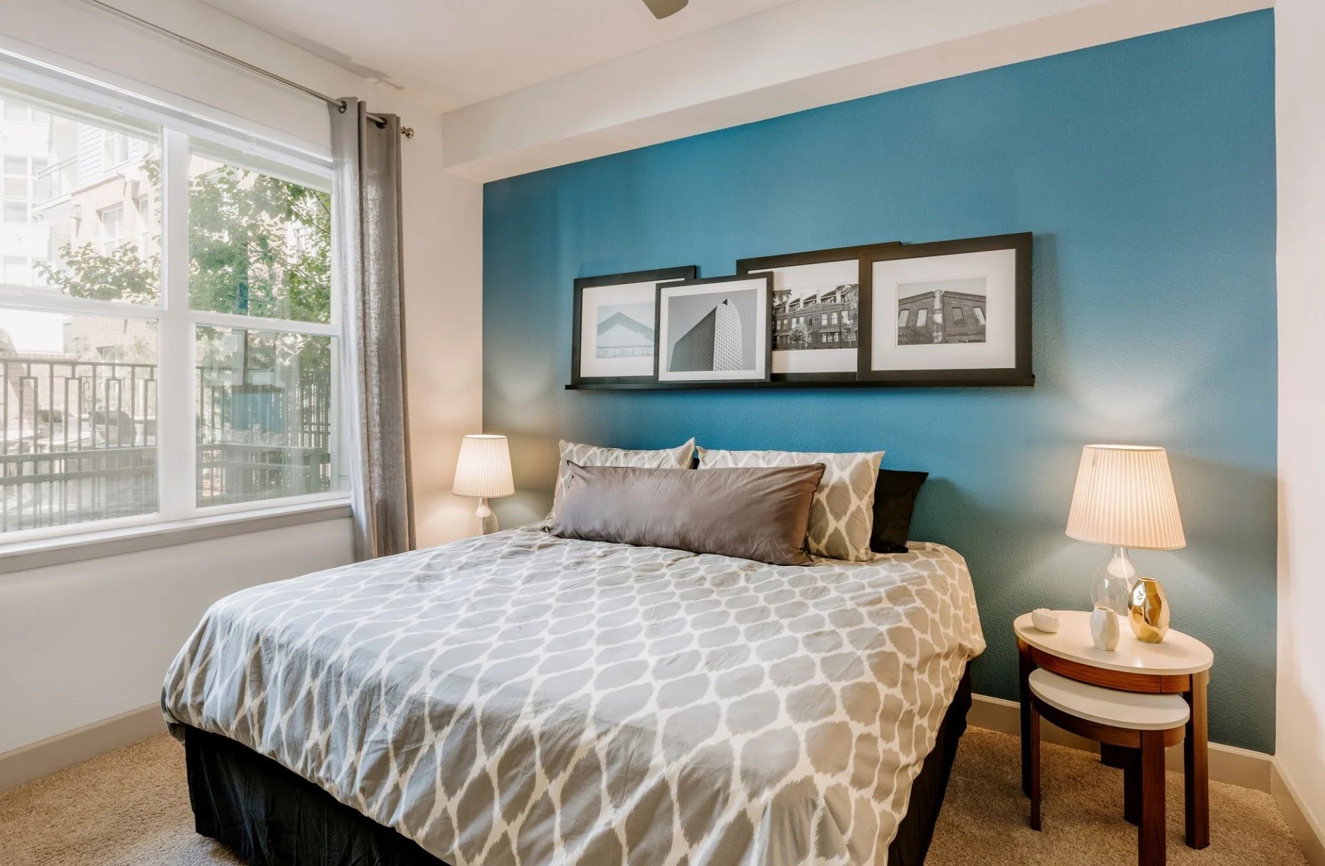 A bedroom with a bed , lamps , and a blue wall.